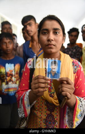 Verwandter von Fabrikarbeiterin aus Bangladesch hält sein Bild in einem Gebäude, wo ihre Körper waren brachte nach einer Explosion ich Stockfoto