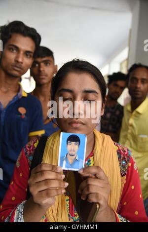 Verwandter von Fabrikarbeiterin aus Bangladesch hält sein Bild in einem Gebäude, wo ihre Körper nach einer Explosion gebracht wurden Stockfoto