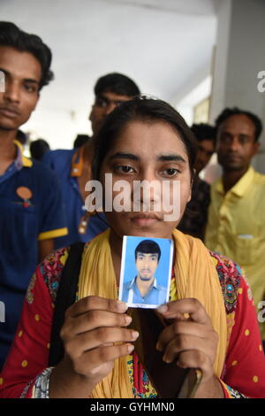 Verwandter von Fabrikarbeiterin aus Bangladesch hält sein Bild in einem Gebäude, wo ihre Körper nach einer Explosion gebracht wurden Stockfoto