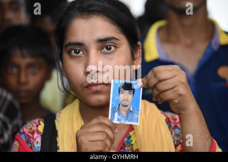 Verwandter von Fabrikarbeiterin aus Bangladesch hält sein Bild in einem Gebäude, wo ihre Körper nach einer Explosion gebracht wurden Stockfoto