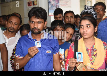 Verwandter von Fabrikarbeiterin aus Bangladesch hält sein Bild in einem Gebäude, wo ihre Körper nach einer Explosion gebracht wurden Stockfoto