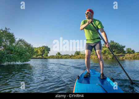 muskulös, senior männlich paddeln einen Stand up Paddleboard auf einem See in Colorado Stockfoto