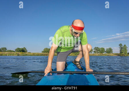 muskulös, senior männlichen Paddler auf einem Stand up Paddleboard auf einem See in Colorado Stockfoto