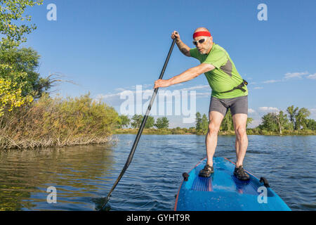 muskulös, senior männlichen Paddler auf einem Stand up Paddleboard auf einem See in Colorado Stockfoto