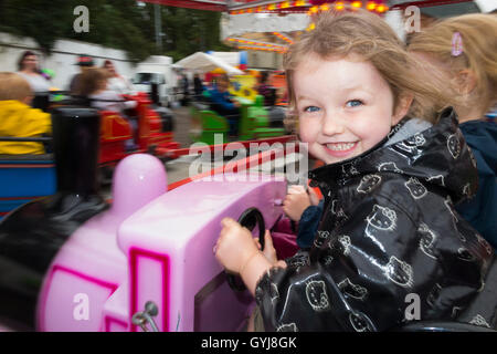 Glücklich lächelnde Kind / Mädchen / Kinder / Mädchen / Kind lächelt / Kinder auf kleine, aber schnell touring Messegelände / Messe Kreisel Stockfoto