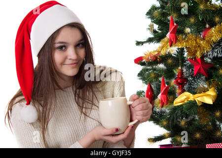 Teenager-Mädchen mit Kaffeetasse unter Weihnachtsbaum Stockfoto