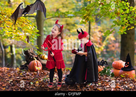 Zwei lustige Kinder tragen Teufel und Vampir Kostüm mit roten Hörnern und Trident Süßes oder Saures an Halloween. Stockfoto