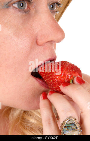 Eine Nahaufnahme Bild einer schönen Frau essen eine große Erdbeere mit blauen Auge des weißen Hintergrund isoliert. Stockfoto