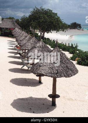 Blick nach unten auf eine Reihe von strohgedeckten Sonnenschirme Schatten Schattenwurf an einem weißen Sandstrand Stockfoto
