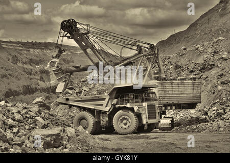 Bagger das Eisenerz auf den Tagebau zu entwickeln und auf den Muldenkipper - schwarz / weiß-Bild laden Stockfoto