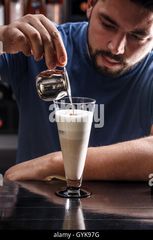 Barista gießt Kaffee in Milch - Kaffee Latte Zubereitung Stockfoto