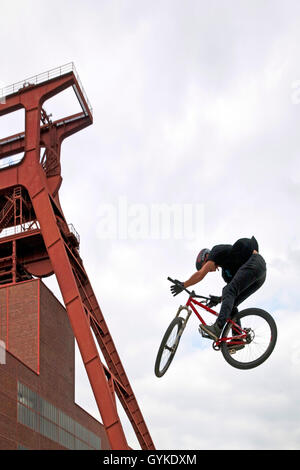 Jumping BMX rider vor kopfbedeckungen der Zeche Zollverein, Deutschland, Nordrhein-Westfalen, Ruhrgebiet, Essen Stockfoto