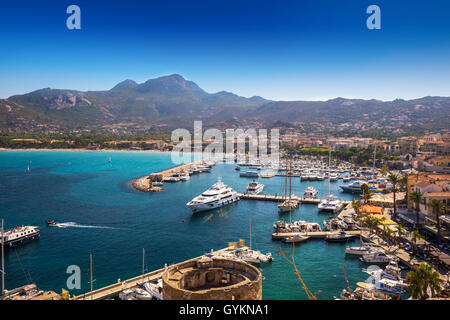Blick auf Calvi Strand, historische Häuser in der Altstadt von Calvi mit türkisblauen glasklaren Meerwasser im Hafen mit Booten und Yachten, Corsica Stockfoto