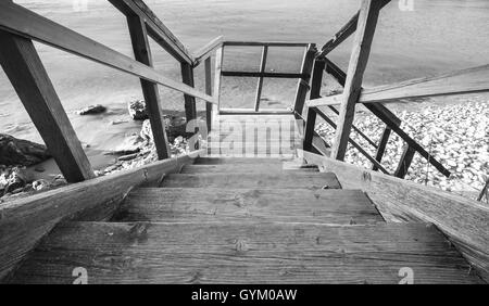 Perspektivische Ansicht der Holztreppen hinunter zur Küste Meeres. Schwarz / weiß Foto Stockfoto