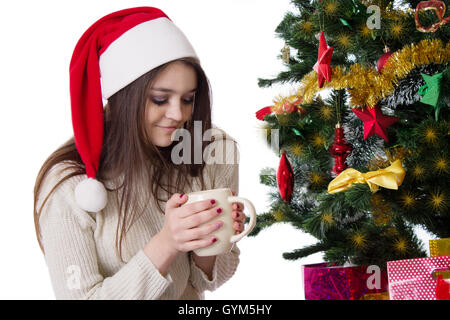 Teenager-Mädchen mit Kaffeetasse unter Weihnachtsbaum Stockfoto