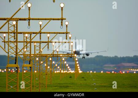 Flugzeug zu landen bei der Ankunft auf dem Flughafen Schiphol hinter Start-und Landebahn Leuchten Stockfoto