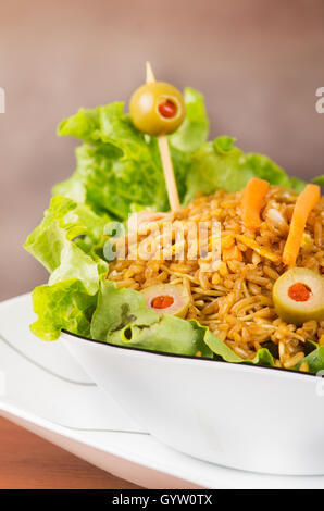 Stilvolle Präsentation Salat, Reis und Oliven in künstlerischen weißen Teller mit abstrakten Hintergrund Stockfoto