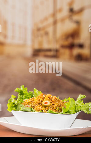 Stilvolle Präsentation Salat, Reis und Oliven in künstlerischen weißen Teller mit abstrakten Hintergrund Stockfoto