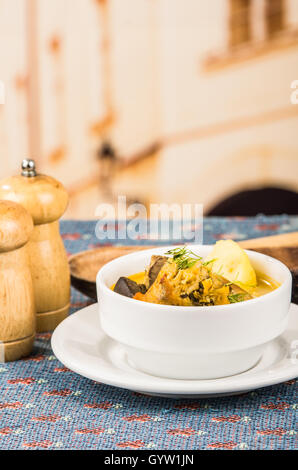 Edel Portion Kartoffel Suppe mit Fleisch und Gemüse, serviert in weißen Schalen auf Tisch, Blaue Tischdecke, Salz Pfefferstreuer, gemütliche Restaurant Hintergrund Stockfoto