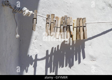 Detail-Wäscheklammern am Seil auf Hintergrund Wand weiß Stockfoto