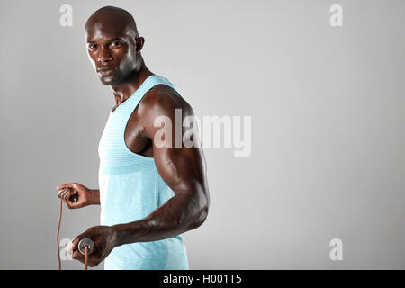 Junge Afrikaner mit Seilspringen vor grauem Hintergrund. Gut aussehend muskulösen Mann posiert mit Seilspringen. Stockfoto
