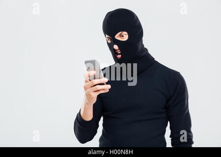 Angry Young Man in Balaclava mit Handy Stockfoto