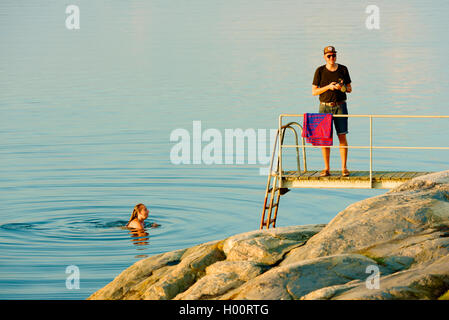 Marstrand, Schweden - 8. September 2016: Dokumentation der Abend Meer in windstillen Wasser Baden. Weibliche in Wasser und männlich auf Pier wi Stockfoto