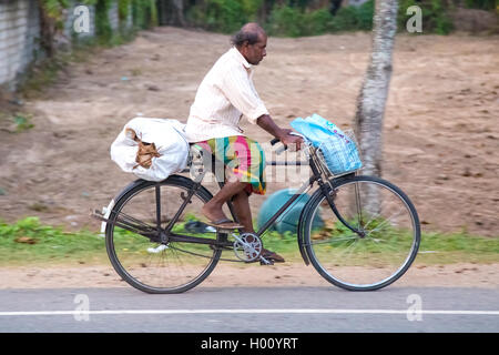 WELIGAMA, SRI LANKA - 7. März 2014: Mann fährt Fahrrad auf Ortsstraße. Radfahren ist der Haupttransport für die traditi Stockfoto