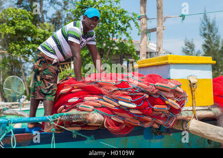 WELIGAMA, SRI LANKA - 7. März 2014: Fischer Vorbereitung Fischernetz auf einem Boot. Tourismus und die Fischerei sind zwei Hauptgeschäft in thi Stockfoto