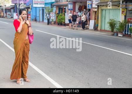 HIKKADUWA, SRI LANKA - 24. Februar 2014: Schöne Frau gekleidet in Sari auf Handy auf Straße. Ca. 45-50 % der Menschen in Sri Lan Stockfoto