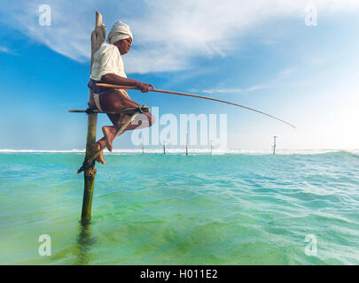 HIKKADUWA, SRI LANKA - 9. März 2014: ältere Stelzenläufer Fischer am Strand von Hikkaduwa. Die meisten realen Stelzenfischer schon lange vorbei. Stockfoto