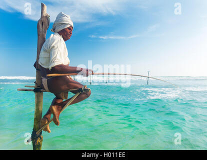 HIKKADUWA, SRI LANKA - 9. März 2014: ältere Stelzenläufer Fischer am Strand von Hikkaduwa. Die meisten realen Stelzenfischer schon lange vorbei. Stockfoto