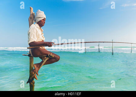 HIKKADUWA, SRI LANKA - 9. März 2014: ältere Stelzenläufer Fischer am Strand von Hikkaduwa. Die meisten realen Stelzenfischer schon lange vorbei. Stockfoto
