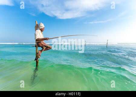 HIKKADUWA, SRI LANKA - 9. März 2014: ältere Stelzenläufer Fischer am Strand von Hikkaduwa. Die meisten realen Stelzenfischer schon lange vorbei. Stockfoto