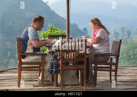 ELLA, SRI LANKA - 3. März 2014: Tourist paar mit Frühstück im Bungalow-Terrasse mit Blick auf Teeplantagen in bac Stockfoto