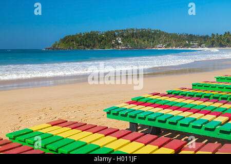 Bunte hölzerne Liegestühle am Strand von Unawatuna in Sri Lanka. Stockfoto