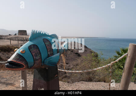 El Cotillo, Fuerteventura, Kanarische Inseln, Spanien: Eine öffentliche Fisch Skulptur mit El Tostón Schloss, ein Wachturm für Verteidigung im 18. Jahrhundert Stockfoto