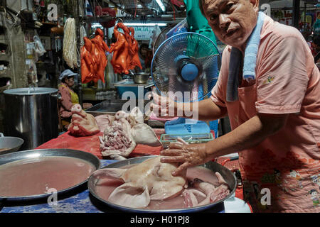 Thailändischer Metzger rasiert Gesicht und Kopf eines Schweins, um auf seinem Marktstand vorzeigbarer zu sein. Thailand S. E. Asien Stockfoto