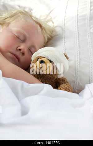 Ein junges Mädchen, schlecht im Bett kuscheln den Teddy, fühlt sich auch schlecht. Stockfoto