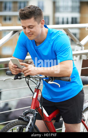 Junger Mann mit Handy während auf Fahrradtour Stockfoto