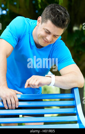 Man Looking At Aktivitätsprotokoll während des Trainings im Park Stockfoto