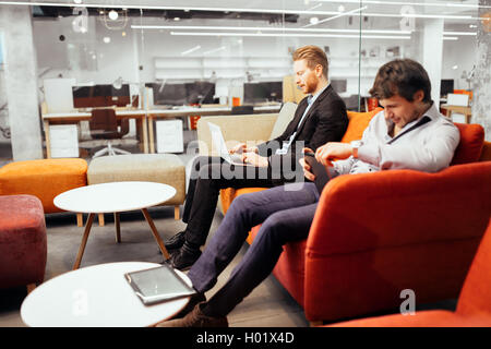 Erfolgreiche Geschäftsleute auf Geräten arbeiten, während Sie gemütlich auf dem sofa Stockfoto