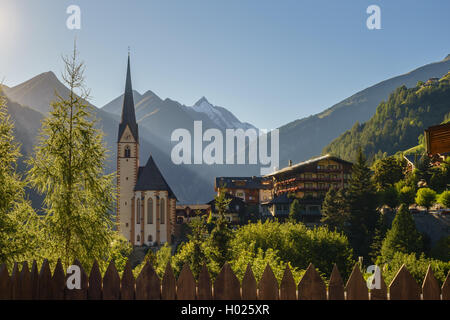 St Vincent Kirche gegen Grossglockner Mountain und hohen Tauern Bereich sonnenbeschienenen von Abendsonne. Heiligenblut, Kärnten, Österreich Stockfoto