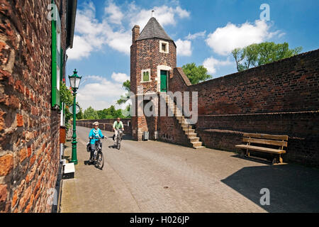 Radfahrer in der Stadt an der Wand und Wand Turm Pfefferbuechse, Deutschland, Nordrhein-Westfalen, Niederrhein, Dormagen Stockfoto