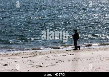 Mensch und Hund Blick auf das Meer vom Strand von Low Newton und St.Mary Oase auf Northumberland Küste Stockfoto