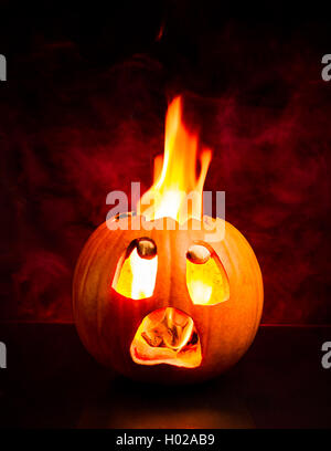 Angst Gesicht des Halloween-Kürbis mit Flammen und roten Rauch im Hintergrund. Stockfoto