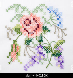 Blumen-Motiv Handstickerei auf weißem Leinen Tischdecke.  Mehrfarbiges Kreuz Stich Dekoration mit Garn. Handarbeit. Makro-Foto Stockfoto