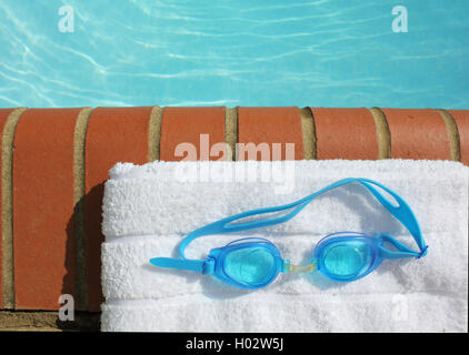 ein paar Schwimmbrillen von einem Pool auf einem weißen Handtuch Stockfoto
