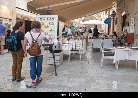 DUBROVNIK, Kroatien - 28. Mai 2014: Touristen auf der Suche im Menü vor der Terrasse des Restaurants. Dubrovnik hat viele Restaurants w Stockfoto