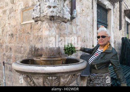 DUBROVNIK, Kroatien - 28. Mai 2014: Ältere Frau trägt Lederjacke Verkauf von Blumen auf Straße. Stockfoto
